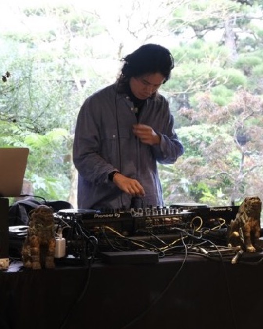 Gene 在和室窗邊演出，窗外可見庭園