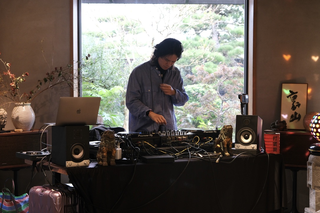 Gene 在和室窗邊演出，窗外可見庭園