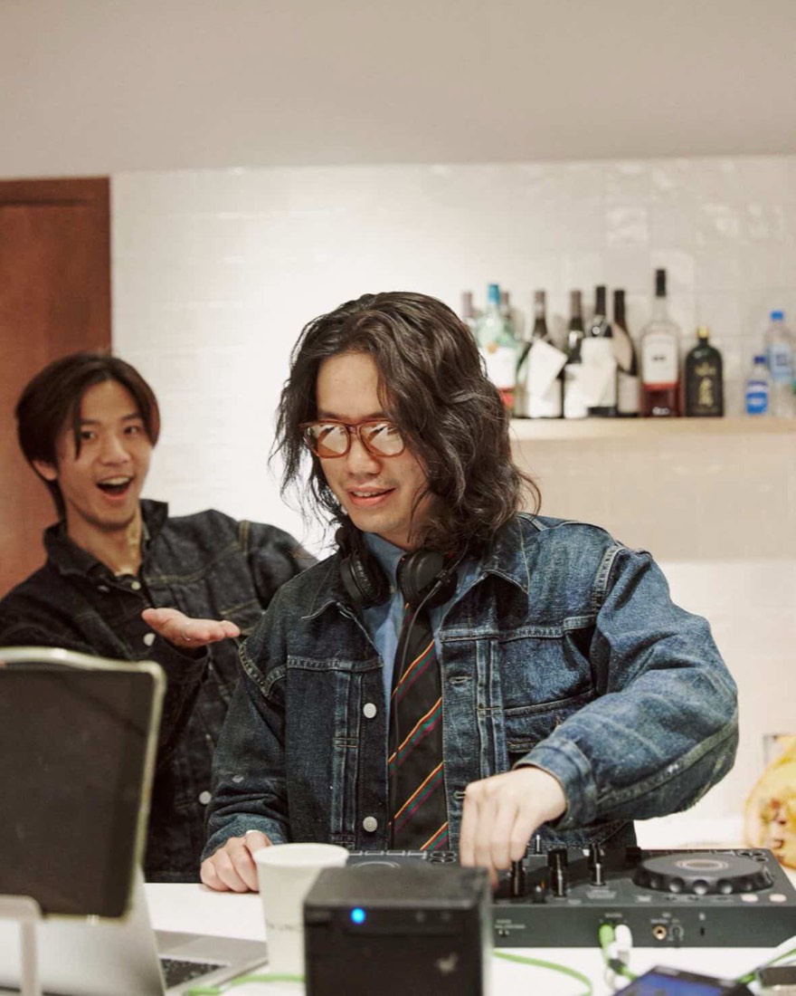 Gene 在吧檯操作控台，後方的朋友驚喜地笑著